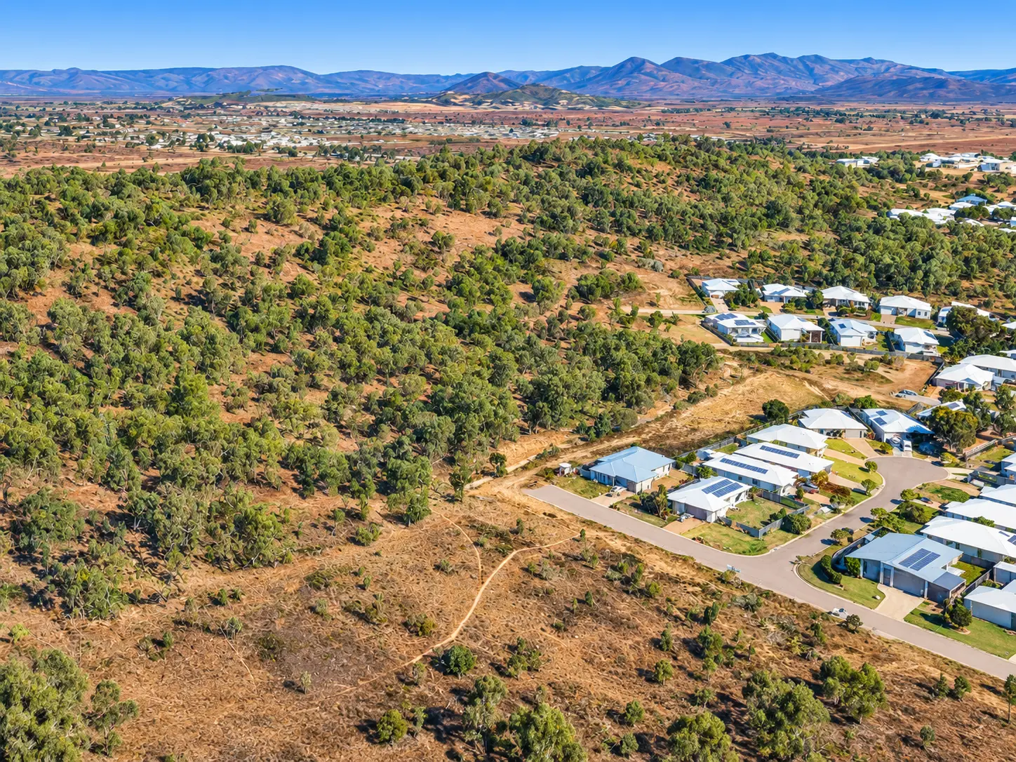 Aerial view of finished homes bordering open bushland and distant ranges at Stages 16 & 17, Beyside, Bushland Beach