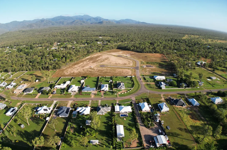 Aerial view of International Palace land beside an established residential neighbourhood, with bushland and the range beyond